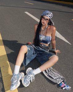 Woman in a leopard print bandana and denim outfit sitting on asphalt
