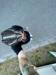 Person with cornrows and tattoos, wearing a t-shirt and bracelet, viewed from above