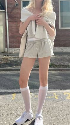 Blonde woman in plaid shorts and white socks standing outdoors
