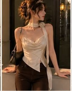 Woman in a cowl neck top and dark pants posing outdoors with soft lighting