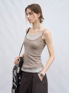 Woman in a layered tank top and dark pants with a bag over her shoulder