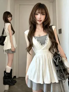 Woman in a white dress over a gray top with a cross necklace and black handbag