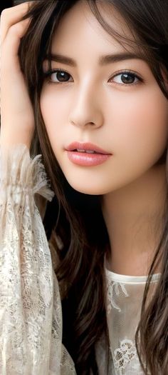 Woman with long dark hair wearing a white lace top, close up portrait