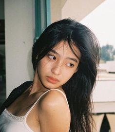 Woman with long black hair wearing a white tank top with lace trim
