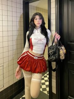 Woman with long black hair wearing a red skirt and crop top indoors