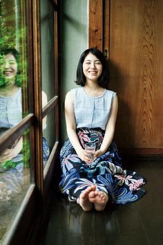 Woman with short hair sitting on a wooden floor, holding a glass