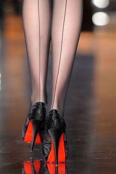 Woman's legs in black seamed stockings and high heels with red soles