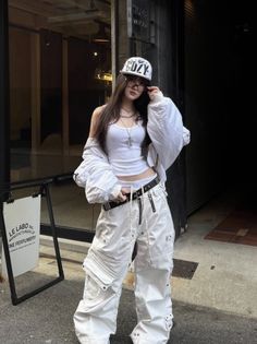 Woman in a white streetwear outfit with cargo pants and a baseball cap outdoors
