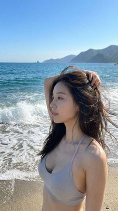 Woman in a bikini top on a beach with mountains in the background