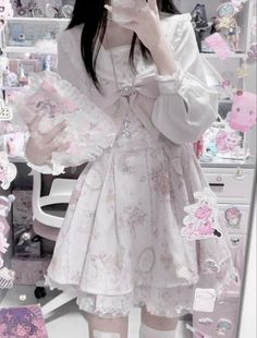 Person in a white blouse and pink lolita dress holding a frilly accessory
