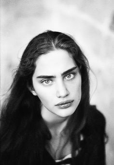 Black and white portrait of a woman with long dark hair and intense gaze