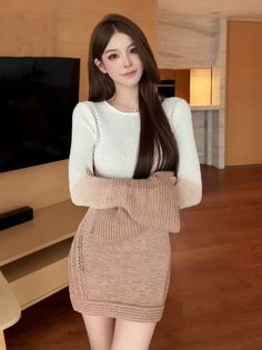 Woman with long brown hair wearing a knitted mini dress indoors