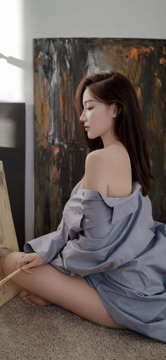 Woman with long hair wearing an off-shoulder shirt, sitting indoors