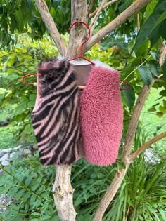 Faux fur vest with zebra print and pink fur hanging on a tree branch