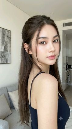 Woman with long brown hair wearing a black top indoors