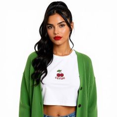 Woman with a ponytail wearing a green cardigan and white crop top