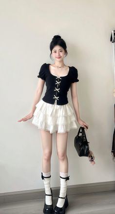 Woman in a black top and white tiered skirt with a black handbag