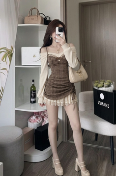 Woman in a plaid dress with lace trim and an off-shoulder top taking a mirror selfie