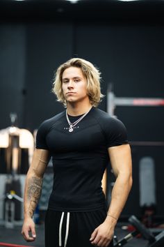Muscular man with blonde long hair wearing a black t-shirt in a gym