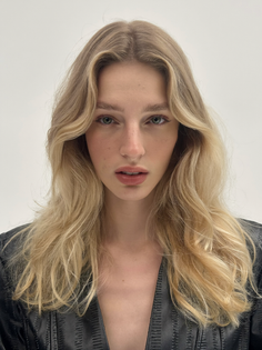 Woman with long blonde wavy hair wearing a black jacket