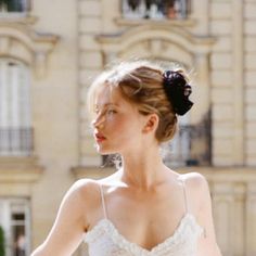 Blonde woman with an updo and white top outdoors in soft lighting