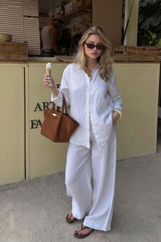 Blonde woman in a white linen outfit holding an ice cream cone outdoors