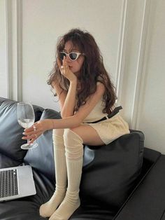 Woman with long wavy hair and sunglasses sitting on a black couch