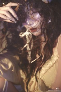 Woman with long dark hair and red lipstick, wearing a top with lace trim