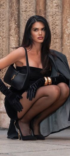 Woman in a black dress, gloves, and stockings posing outdoors