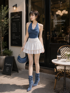 Woman in a blue halter top and white mini skirt standing outside a cafe