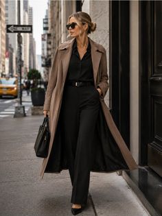 Woman in a trench coat and black outfit walking on a city street