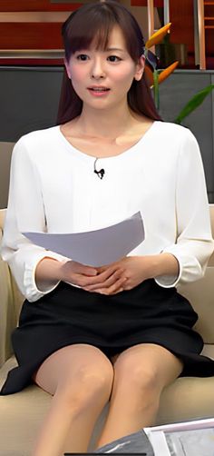 Woman in a white blouse and black skirt with nude pantyhose sitting indoors