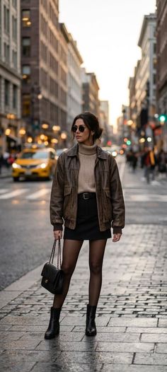 Woman in a brown leather jacket and mini skirt on a city street at golden hour