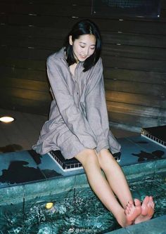 Woman with short hair sitting with her feet in water