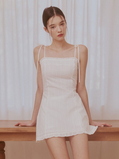 Woman in a white dress leaning on a wooden table with soft lighting