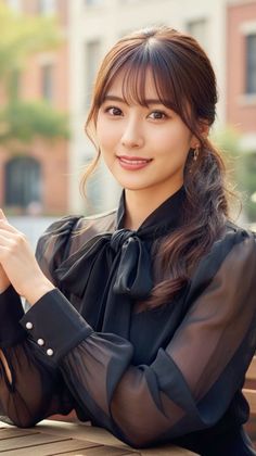 Woman in a black sheer blouse with a bow collar and a ponytail outdoors