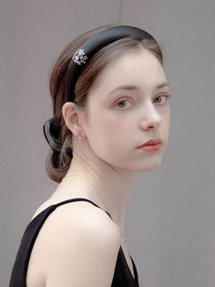 Woman with a black headband and black top looking over her shoulder