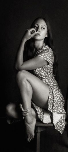 Woman in a floral dress with long hair, sitting in a dramatic pose