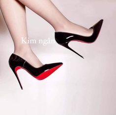 Pair of black high heels with red soles on a light background