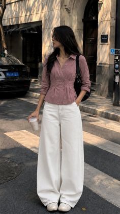 Woman in a striped shirt and wide leg pants standing on a street