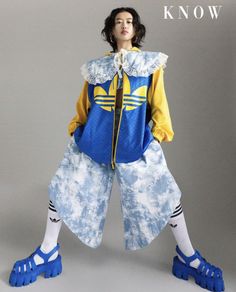 Woman with short hair in a blue and yellow jacket and tie-dye pants