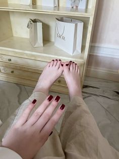 Person with red nail polish on fingers and toes, with a Dior bag in the background