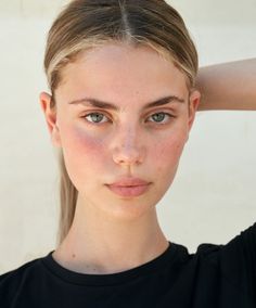 Young woman with blonde hair in a ponytail and green eyes looking at the camera