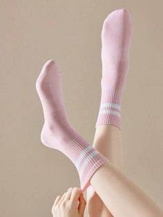 Person wearing pink socks with white stripes, pulling one up