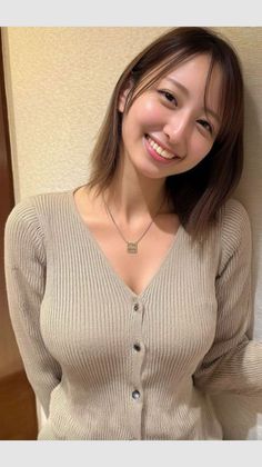 Woman in a ribbed cardigan with a necklace, smiling at the camera