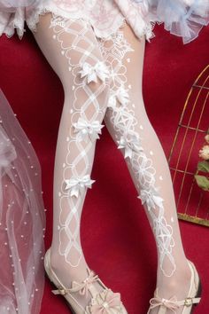 Legs wearing white stockings with bows and mary jane shoes on a red background
