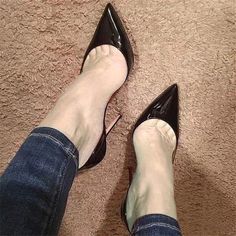 Person wearing black high heels and jeans on a brown carpet