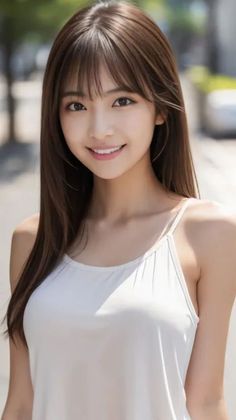 Smiling woman with long brown hair wearing a white top outdoors