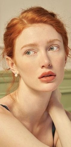 Woman with red hair and green eyes wearing pearl earrings