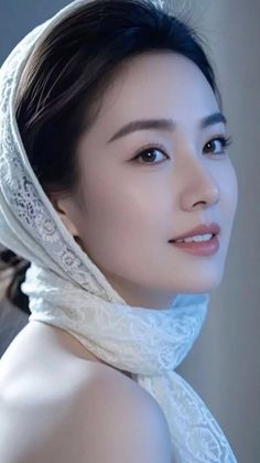 Woman with a white lace headscarf and exposed shoulder, looking at the camera